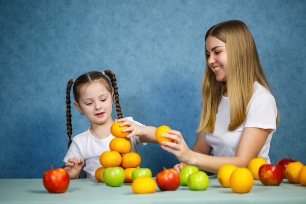 Mała Dziewczynka I Mama Bawią Się Owocami I Wygłupiają. Noszą T-shirty