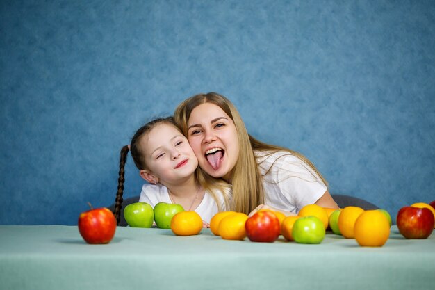 Mała dziewczynka i mama bawią się owocami i wygłupiają. Noszą t-shirty