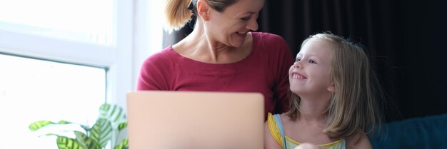 Mała Dziewczynka I Mama Siedzą Na Kanapie Z Laptopem Na Kolanach I Rozmawiają