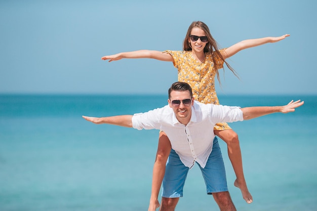 Mała dziewczynka i szczęśliwy tata bawią się podczas wakacji na plaży