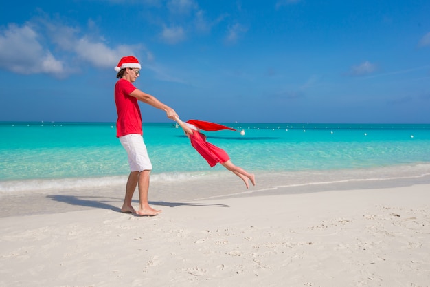 Mała dziewczynka i szczęśliwy tata w Santa Hat ma zabawę podczas wakacje