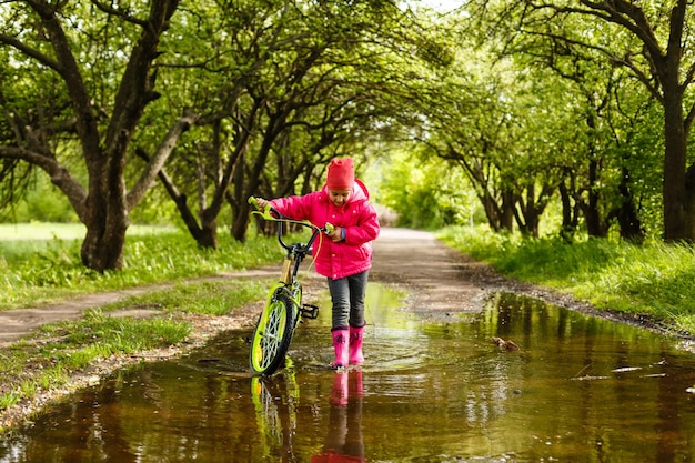 mała dziewczynka jedzie na rowerze w kałuży wody