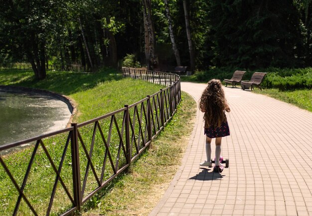 Mała dziewczynka jeździ na hulajnodze w parku