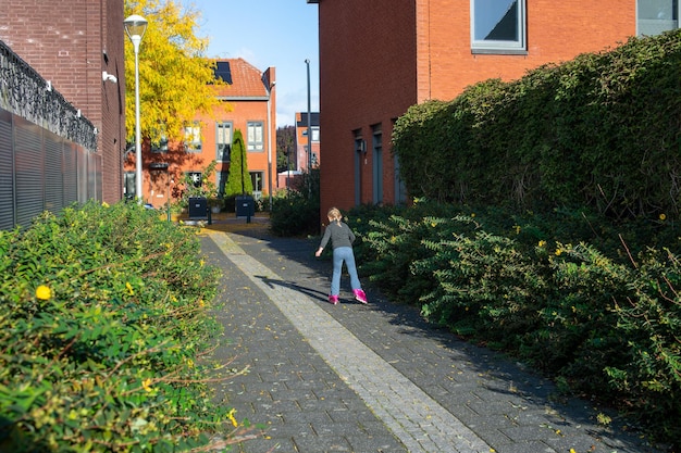 Mała dziewczynka jeździ na rolkach na podwórku domu na wiosnę