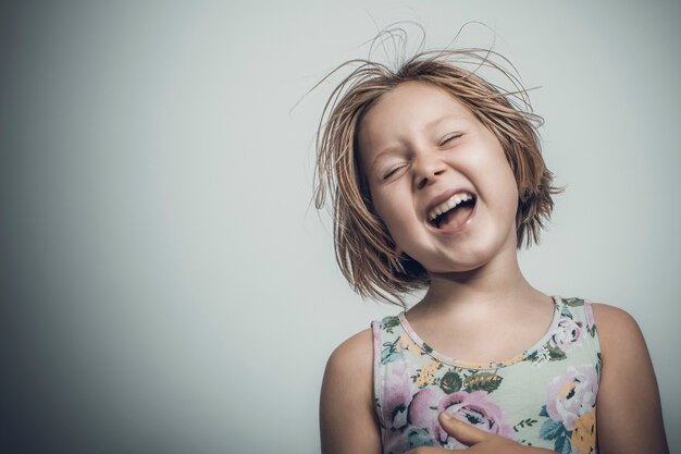 Mała dziewczynka kaukaski z krótkimi włosami śmiejąc się beztroski. portret studyjny