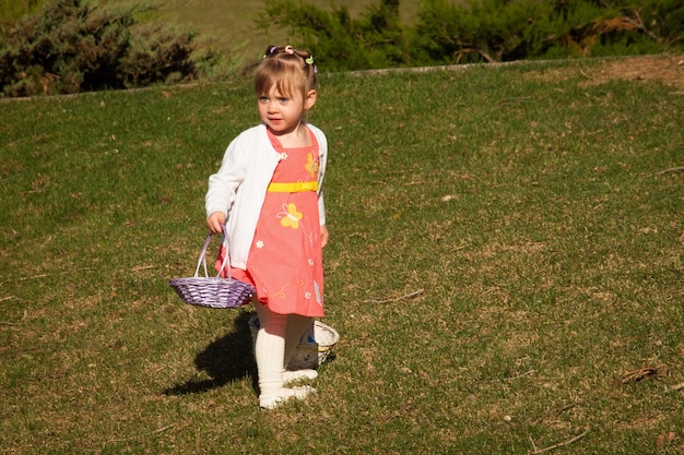 Mała dziewczynka malucha na polowanie na jajka wielkanocne w parku miejskim.