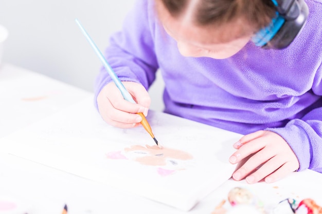 Zdjęcie mała dziewczynka maluje na płótnie farbą akrylową.