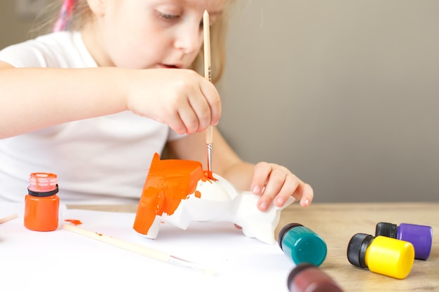 Mała dziewczynka maluje zabawkowego lisa z gliny koncepcja DIY