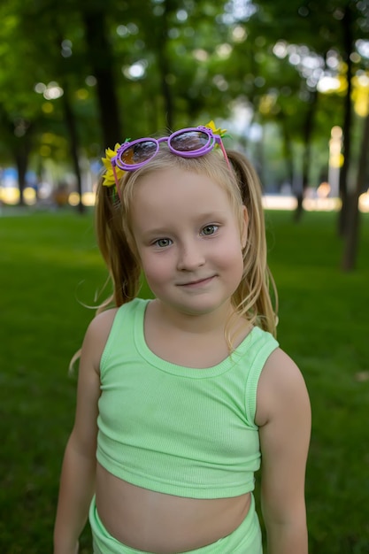 Mała dziewczynka modelka pozuje w parku w zielonym garniturze