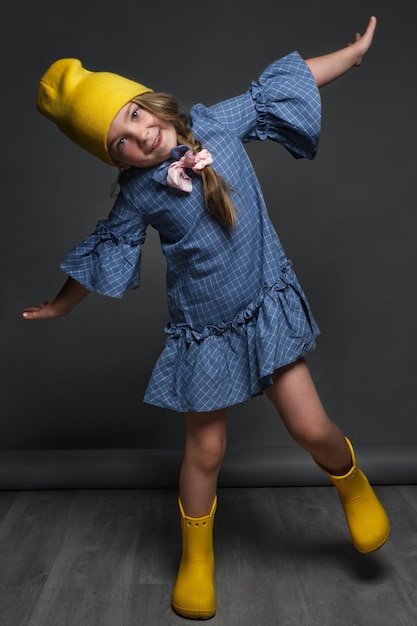 Mała dziewczynka modelka profesjonalnie pozująca w studio w sukience i żółtym kapeluszu Testy modeli