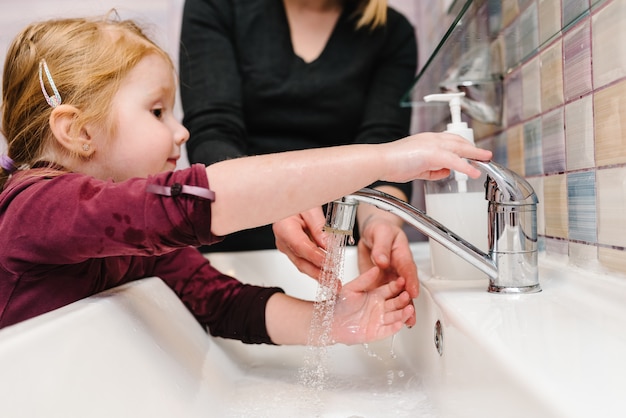 Zdjęcie mała dziewczynka myje jej ręki w łazienka zlew. myć dłonie