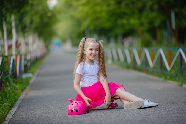 Mała dziewczynka na deskorolce w parku latem
