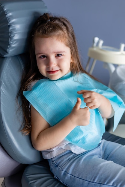 Mała dziewczynka na fotelu dentystycznym uśmiecha się do kamery.