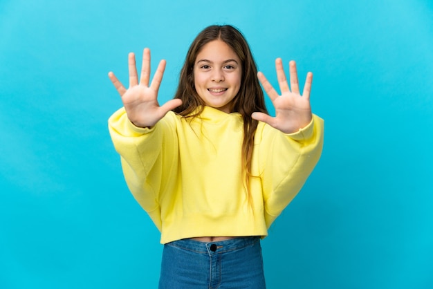 Zdjęcie mała dziewczynka na odosobnionym niebieskim tle, licząc dziesięć palcami