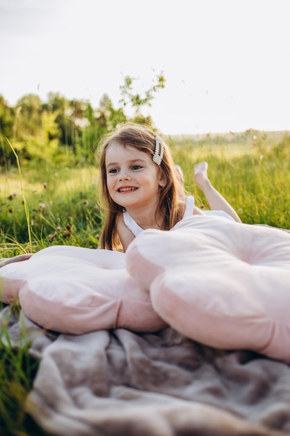 Mała dziewczynka na polu z rolkami siana o zachodzie słońca