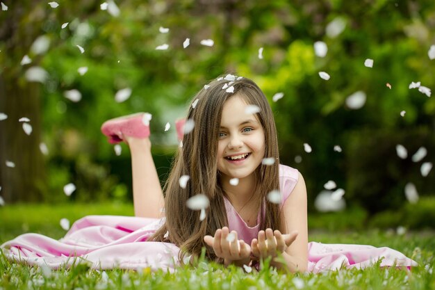 Mała dziewczynka na zielonej trawie z płatkami