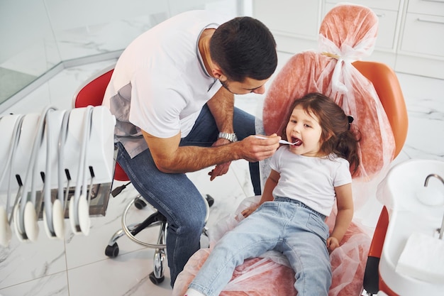Mała dziewczynka odwiedzająca męskiego dentystę w klinice Koncepcja stomatologii