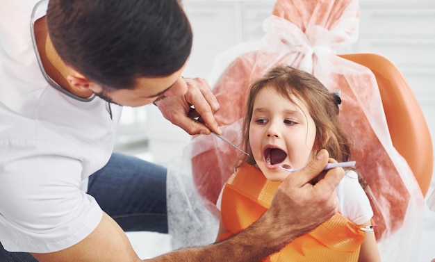 Mała dziewczynka odwiedzająca męskiego dentystę w klinice Koncepcja stomatologii