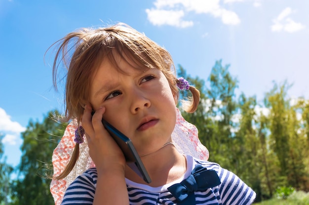 Mała dziewczynka patrząc w górę i mówiąc przez telefon komórkowy