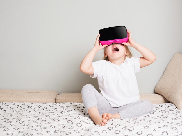 Mała dziewczynka patrząc w okularach wirtualnej rzeczywistości w domu. Skandynawskie wnętrze