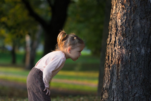 Mała dziewczynka patrzy uważnie na drzewo i studiuje coś na nim