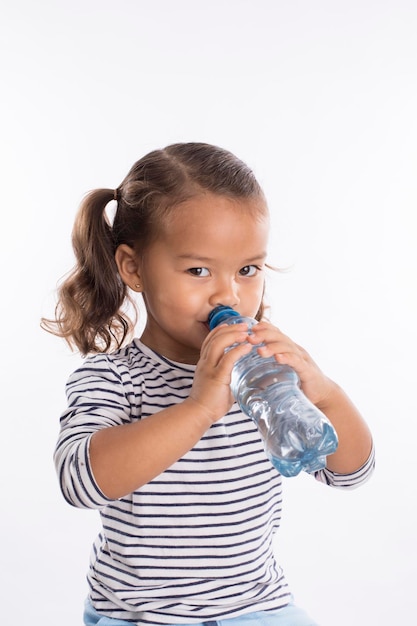 Zdjęcie mała dziewczynka pije wodę butelkowaną portret makiety wyrażeń wracając do szkoły z maską