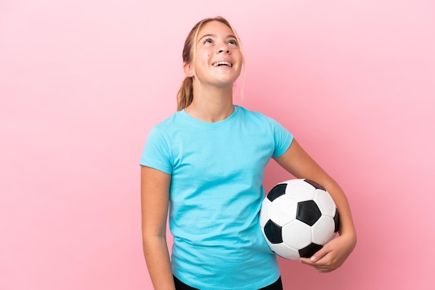 Mała dziewczynka piłkarz odizolowana na różowym tle śmiejąca się