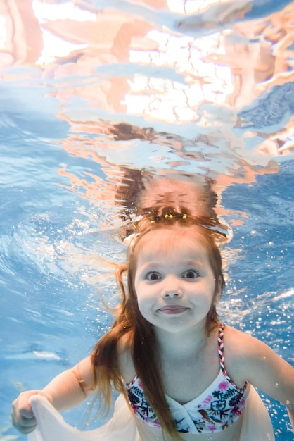 Mała dziewczynka pływa pod wodą w brodziku Nurkowanie Nauka pływania dziecka Ciesz się pływaniem i bąbelkami