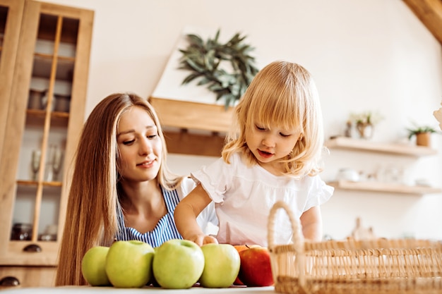 Mała dziewczynka pomaga mamie wybrać jabłka