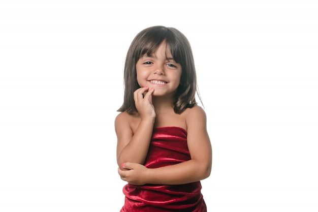 Mała dziewczynka pozuje z czerwoną aksamit suknią na białym tle