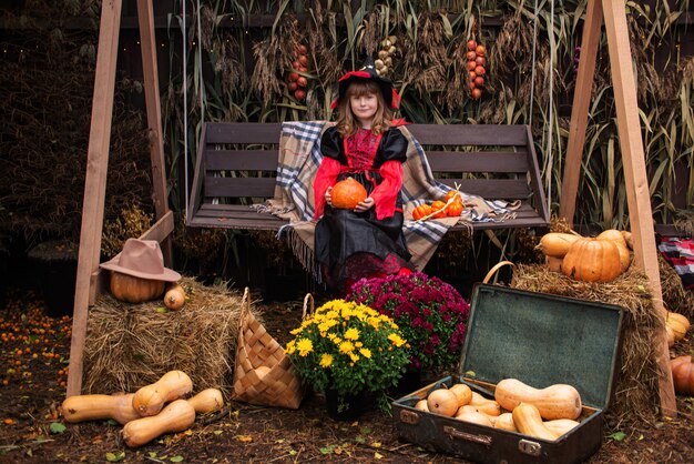 Zdjęcie mała dziewczynka przebrana za wiedźmę z dynią świętuje halloween