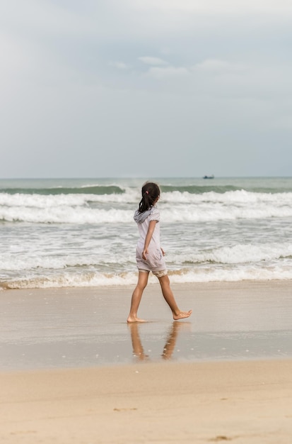 Mała dziewczynka przechodząca na China Beach w Danang w Wietnamie. Bez twarzy