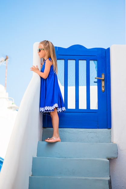 Mała dziewczynka przy ulicą typowa grecka wioska z białymi ścianami i krokami w Grecja