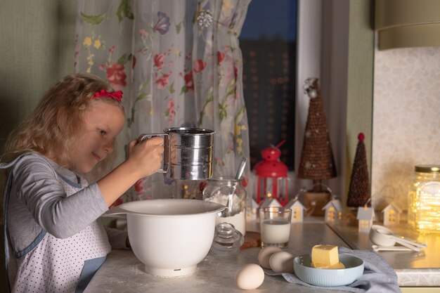 Zdjęcie mała dziewczynka przygotowuje ciasto w misce przed ozdób choinkowych