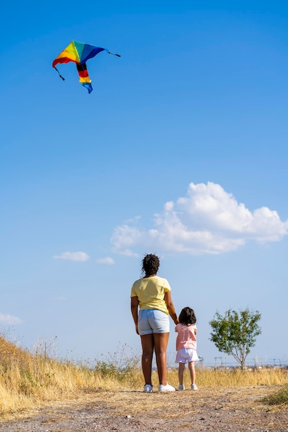 Mała dziewczynka puszcza swój tęczowy latawiec w polu