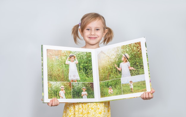 Mała Dziewczynka Rasy Kaukaskiej Trzymająca W Rękach Fotoksiążkę Z Fotografiami