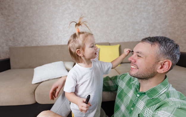 Zdjęcie mała dziewczynka robi makijaż ojcu podczas wspólnych gier