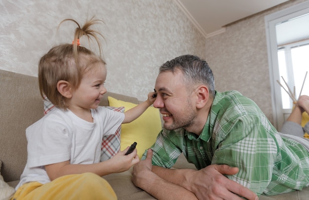 Mała dziewczynka robi makijaż ojcu podczas wspólnych gier