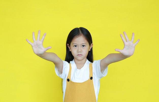 Zdjęcie mała dziewczynka robi przerwie śpiewać z dwa palmą ręki na żółtym tle