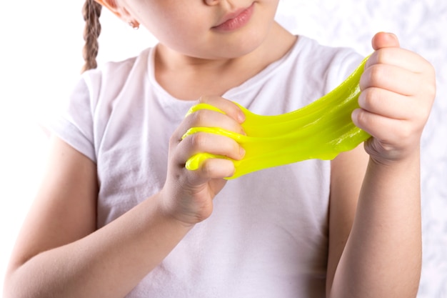 Mała dziewczynka rozciąga żółty śluz w jej rękach.