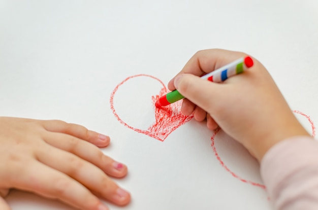 Mała dziewczynka rysuje serce czerwoną kredą - wysoki kąt obrazu z selektywną ostrością. Koncepcja walentynek