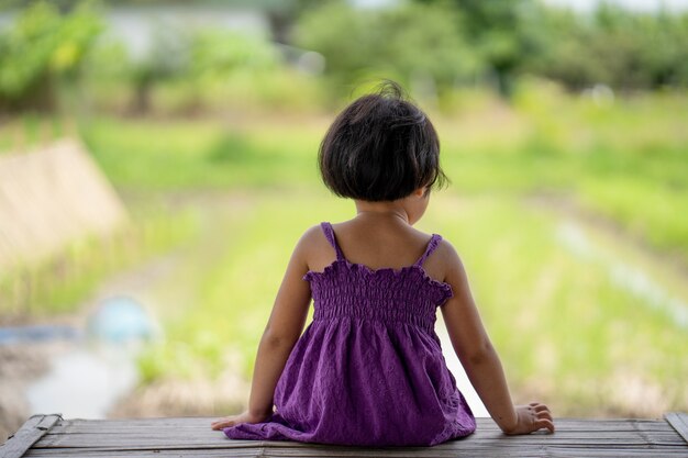 Mała dziewczynka siedzi na drewnianym stole na polu ryżowym
