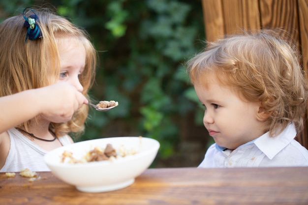 Zdjęcie mała dziewczynka siostra karmi dziecko słodkie jedzenie dla niemowląt jedzenie dzieci