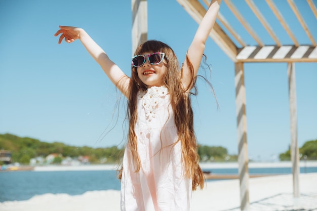 Mała dziewczynka skacze na plaży nad brzegiem miejskiej plaży w letnie wakacje