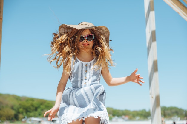 Mała dziewczynka skacze na plaży nad brzegiem miejskiej plaży w letnie wakacje