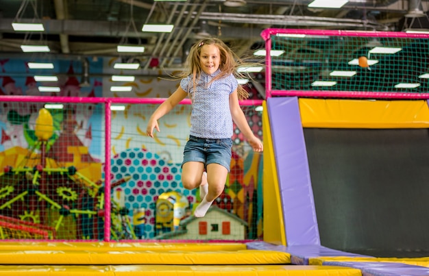Mała dziewczynka skacze na trampolinie w parku rozrywki