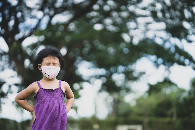 Mała dziewczynka smutny wyraz twarzy noszący maskę ochronną chodzącą po polu