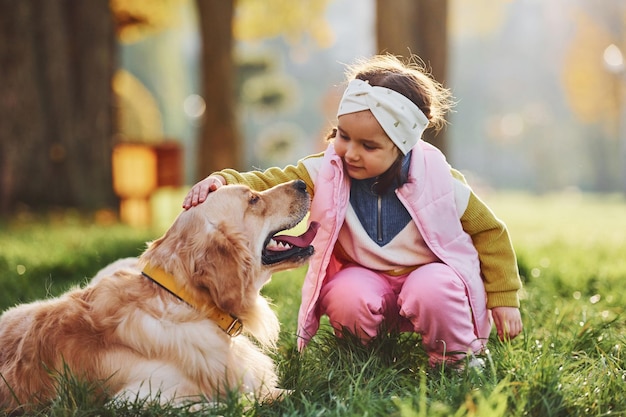 Zdjęcie mała dziewczynka spaceruje z psem golden retriever w parku w ciągu dnia