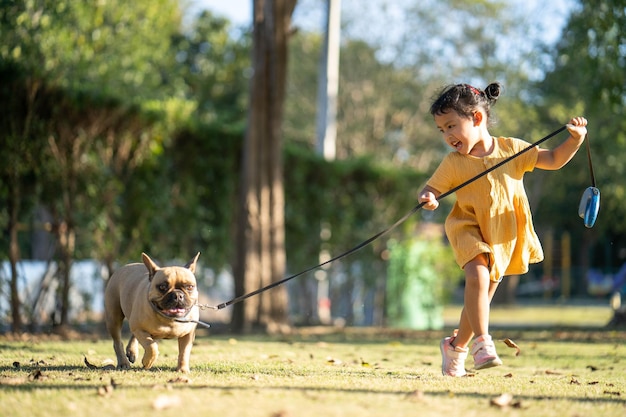 Mała dziewczynka spaceruje z psem w parku