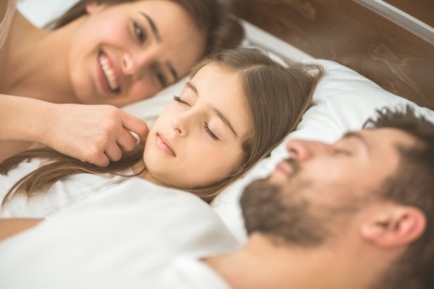 Mała dziewczynka śpi obok rodziców w łóżku